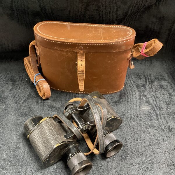 Vintage military binoculars and leather case, side view.