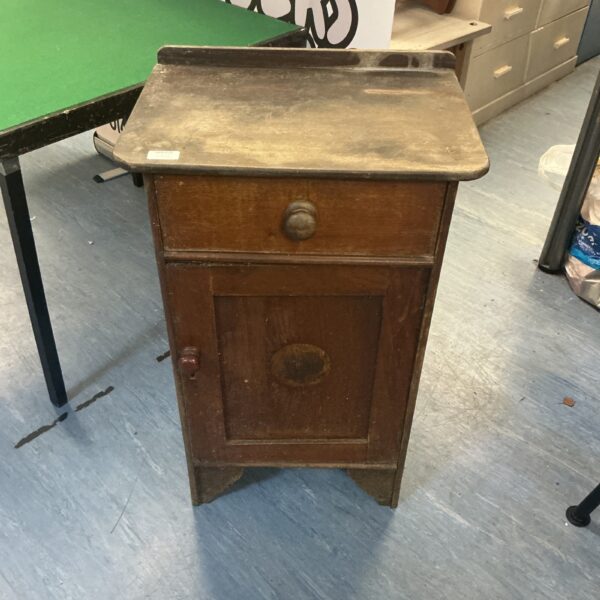 Front view of a vintage oak side cupboard with a drawer and door.
