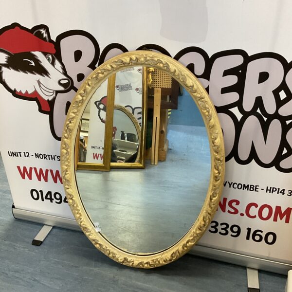Vintage oval hall mirror with ornate gilded frame.