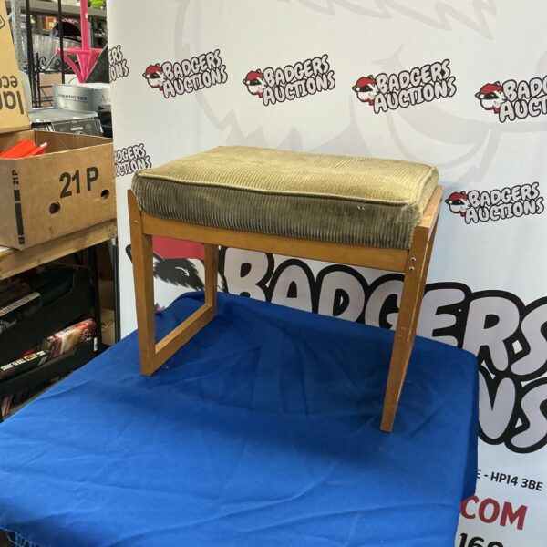 Vintage padded footstool with patterned fabric upholstery.