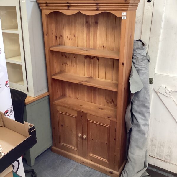 Vintage pine bookshelf with closed storage, ideal for home display.