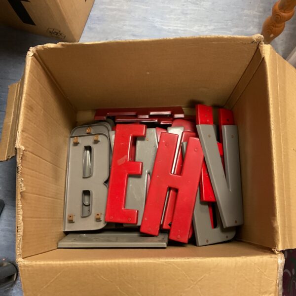 Vintage grey and red plastic letter signs in a cardboard box.