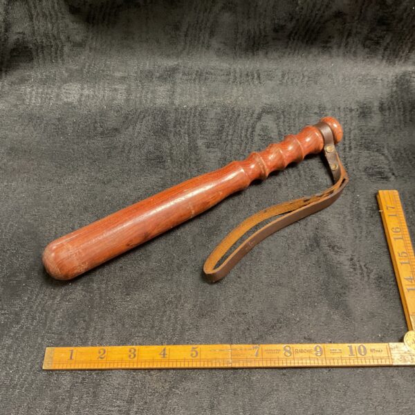 Vintage police truncheon with leather strap, collectible law enforcement item.