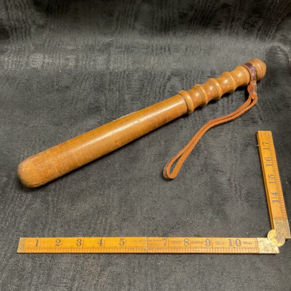 Vintage police truncheon with leather wrist strap, collectible item.