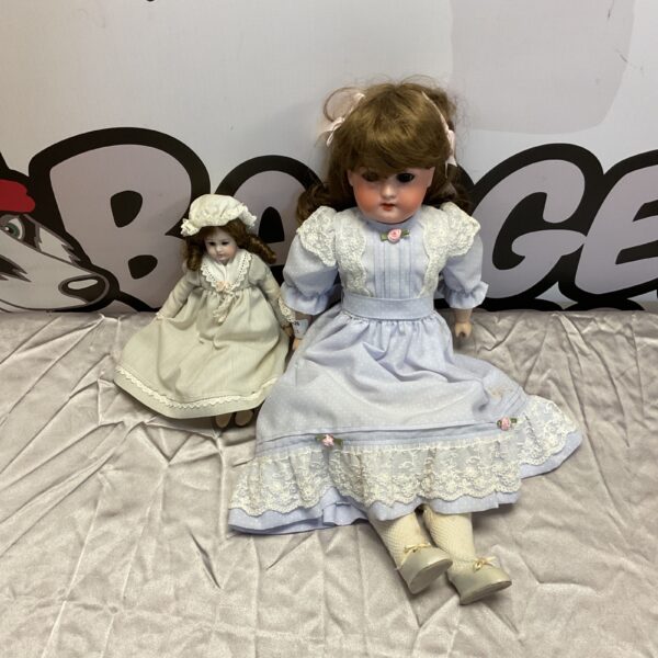 Pair of vintage porcelain dolls in Victorian dresses.