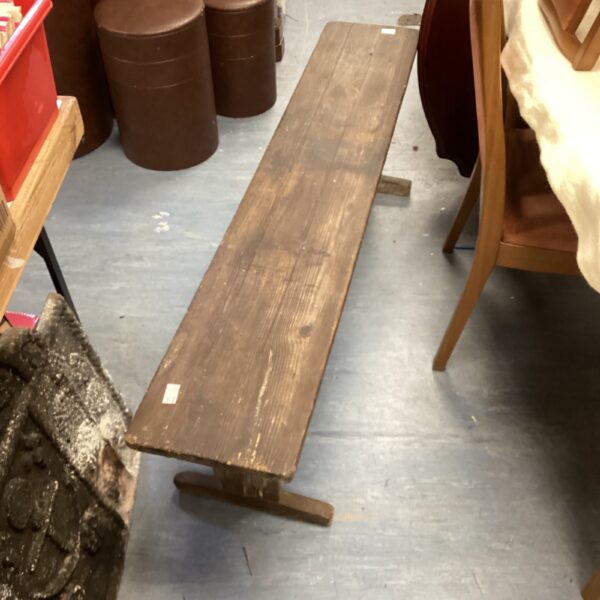 Side view of a vintage wooden school bench with rustic patina.