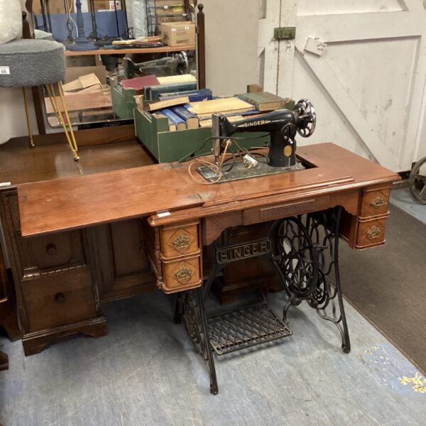 Vintage Singer sewing machine with wooden cabinet and accessories.