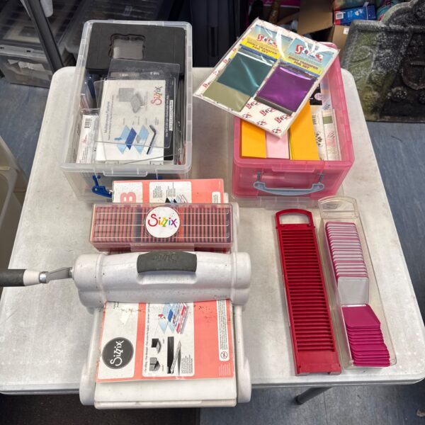 Vintage Sizzix embossing machine with crafting accessories and paper.