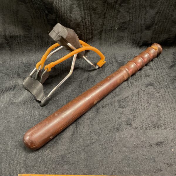 Vintage Black Widow slingshot and wooden police truncheon, collectible sporting goods.