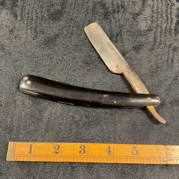 Vintage straight razor with dark handle and steel blade.