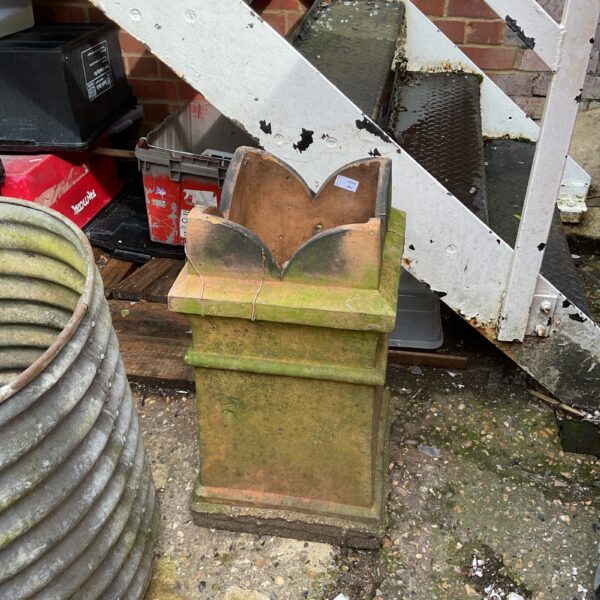 Weathered vintage terracotta chimney pot in a garden setting.