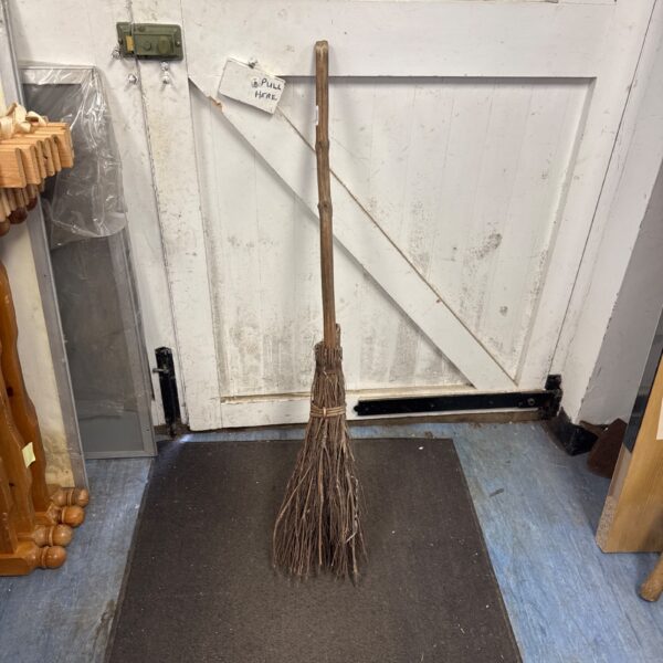 Vintage witch’s broom with natural bristles and wooden handle.