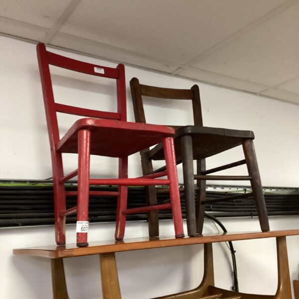 Pair of vintage wooden chairs, one red, showing age and wear.