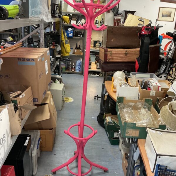Vintage wooden coat and hat stand in a cluttered room.