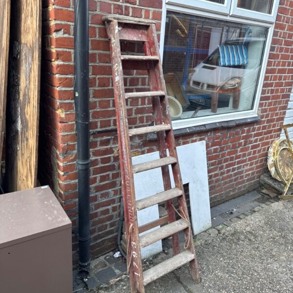 Vintage wooden step ladder leaning against a brick wall.