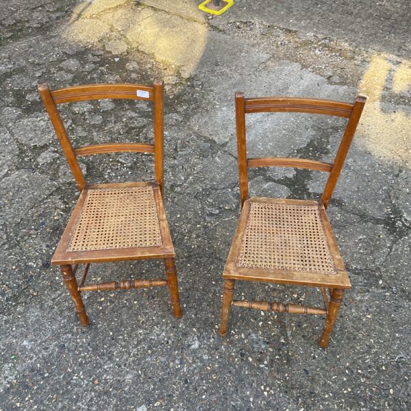 Pair of vintage wooden chairs with wicker seats.