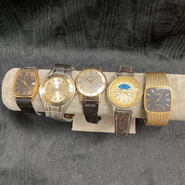 Assorted vintage wristwatches displayed on a dark surface.