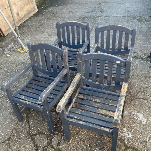 Set of four weathered wooden garden chairs in a garden setting.