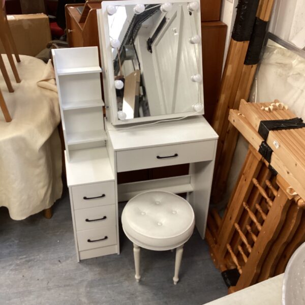White dressing table with illuminated mirror and stool for bedroom use.