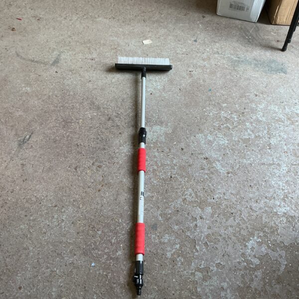 Window cleaning lance with brush head and red grip.