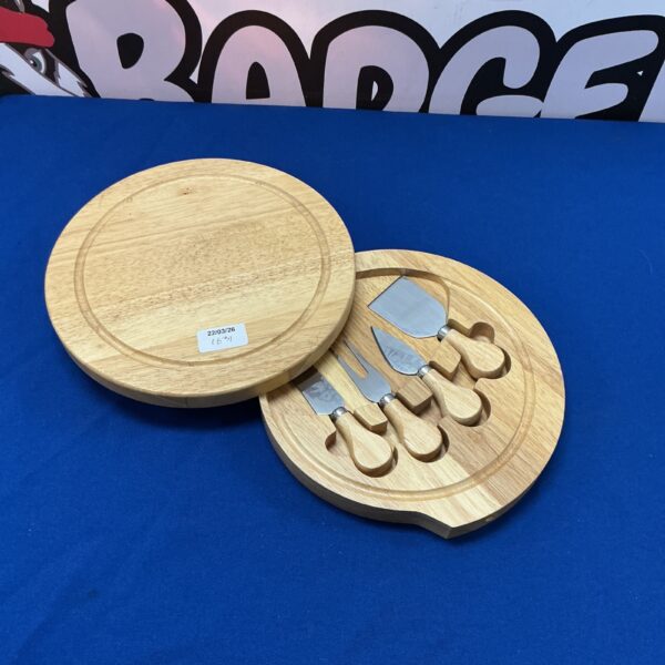 Wooden cheeseboard with three cheese knives for serving.