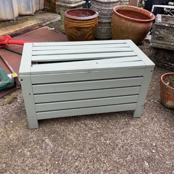 Rustic wooden storage box in a garden setting.