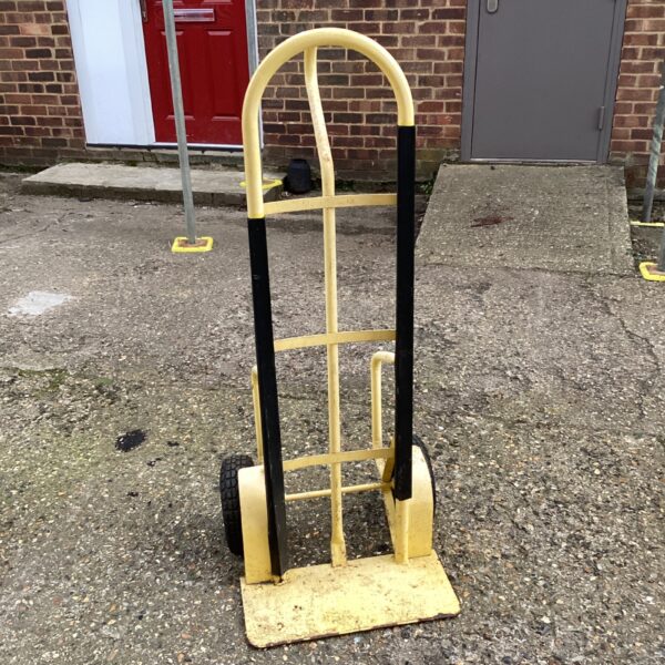 Yellow industrial sack barrow with pneumatic tyre for moving loads.