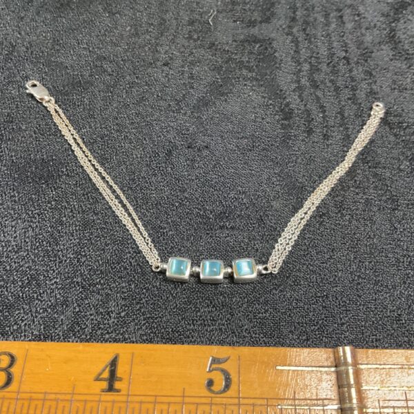 Close-up of 925 silver bracelet with blue stones and triple chain.