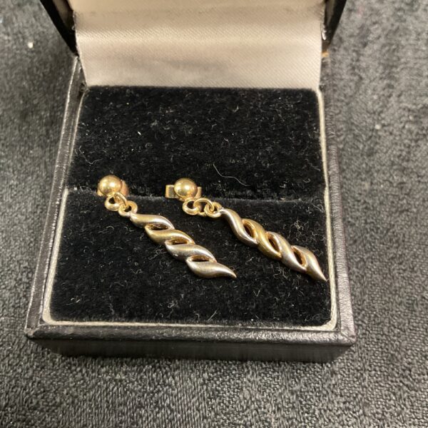 Pair of elegant 9ct gold earrings on a display cushion.
