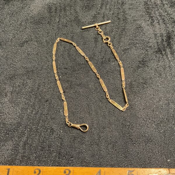 Antique 9ct gold fob chain on dark fabric background.