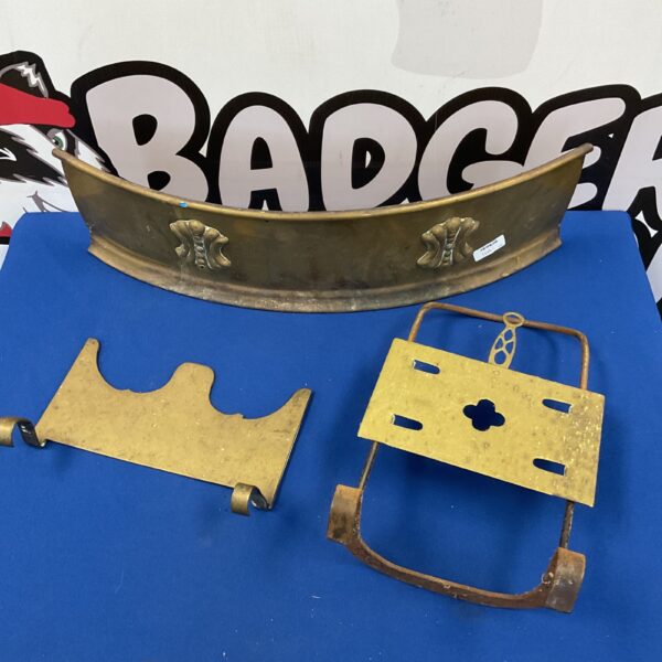 Antique brass fender and trivets on a patterned background.