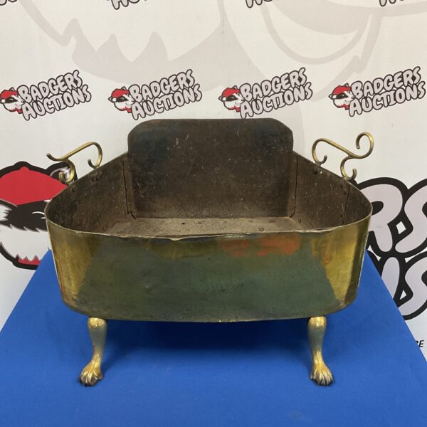 Antique brass fire basket with claw feet for a vintage fireplace.