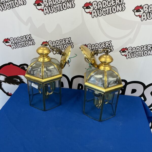 Two antique brass wall lanterns with clear glass panels.