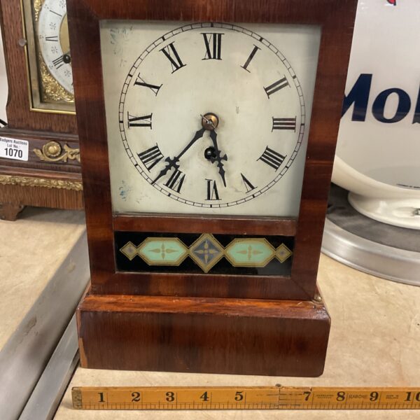 Antique mantle clock with glass door and pendulum.