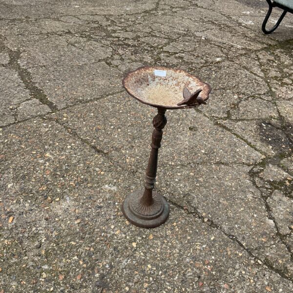 Vintage metal bird bath in a garden setting.