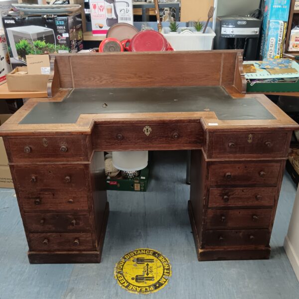 Antique oak executive desk with leather top and drawers.