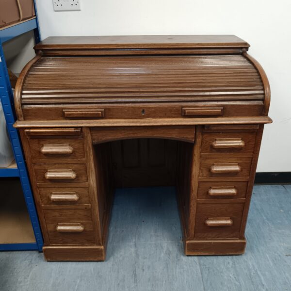 Front view of antique oak roll top desk with drawers.