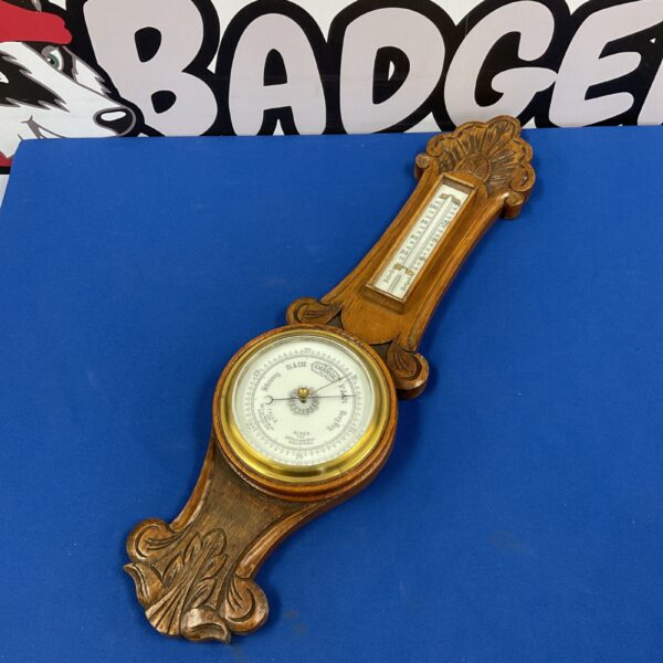 Antique oak wall barometer with mercury thermometer and ornate detailing.