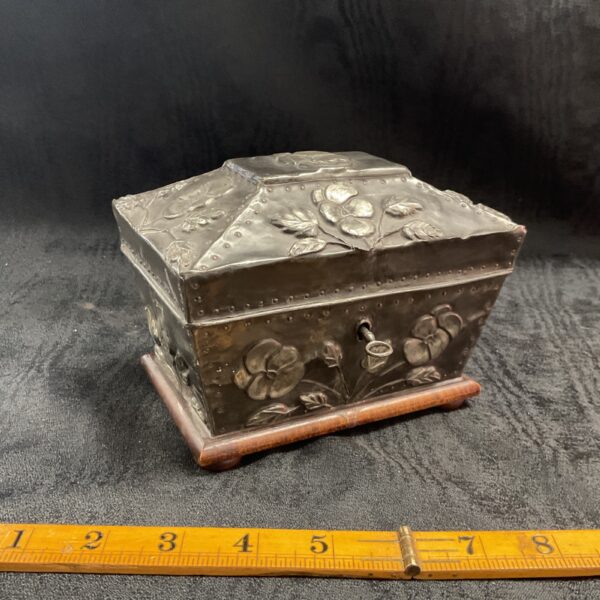 Antique pewter tea caddy with floral embossing, front view.