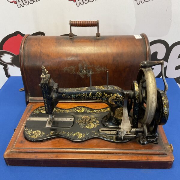 Antique Singer treadle sewing machine in wooden cabinet.
