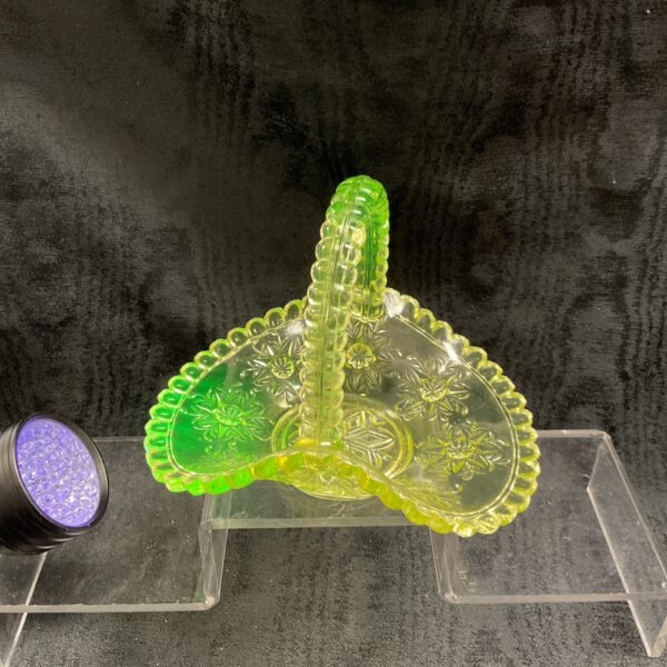 Antique uranium glass basket glowing green under UV light.