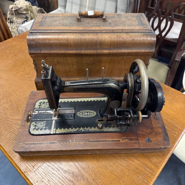 Antique W.J.H. & Co Ltd sewing machine in wooden cabinet.