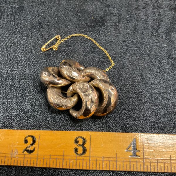 Antique yellow metal brooch with detailed floral design.