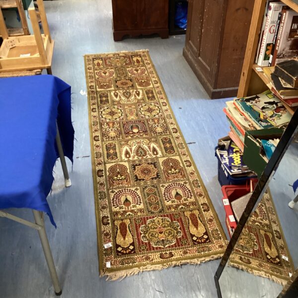 Green geometric Arabic runner rug in a hallway setting.