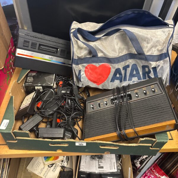 Vintage Atari 2600 consoles with joysticks and carrying bag.