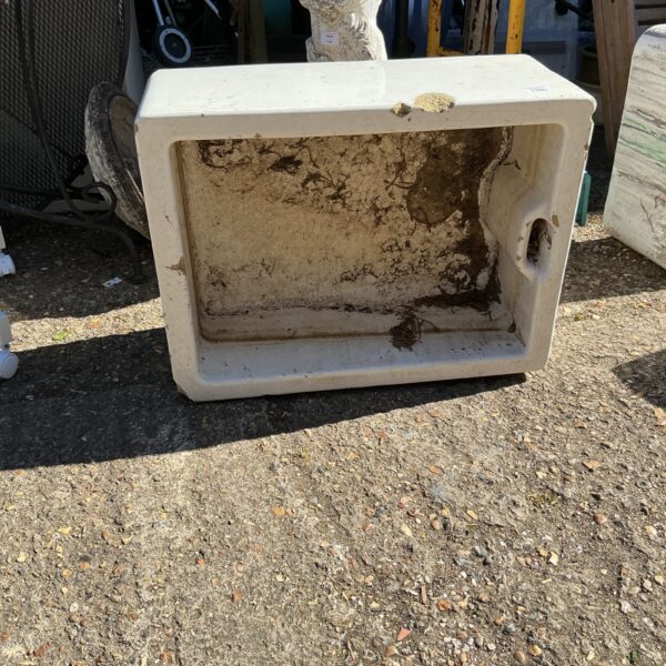 Vintage belfast sink repurposed as a garden planter in an outdoor setting.