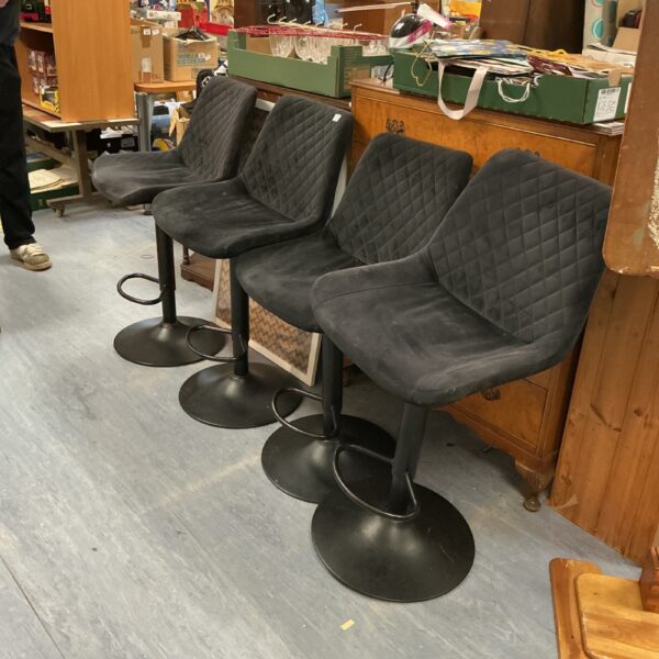 Four black adjustable bar stools for kitchen or home bar seating.