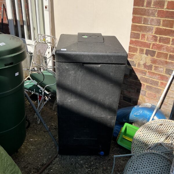 Black plastic compost bin in a garden setting.