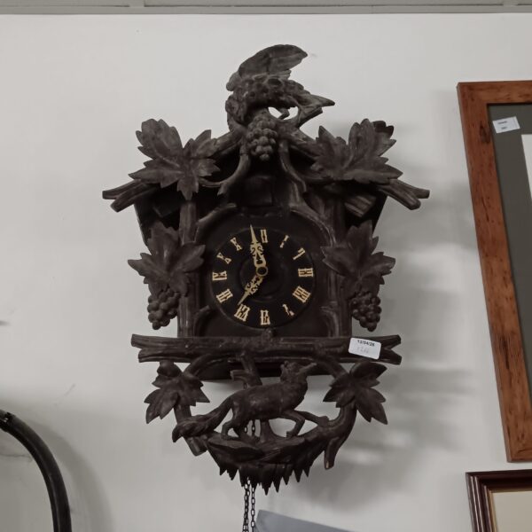Detailed antique Black Forest cuckoo clock with weights and pendulum.