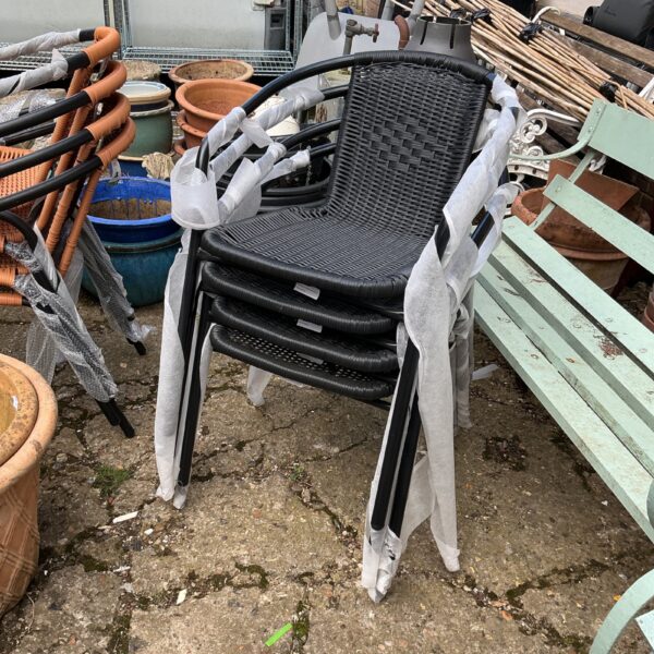 Four black plastic garden stacking seats stacked together.